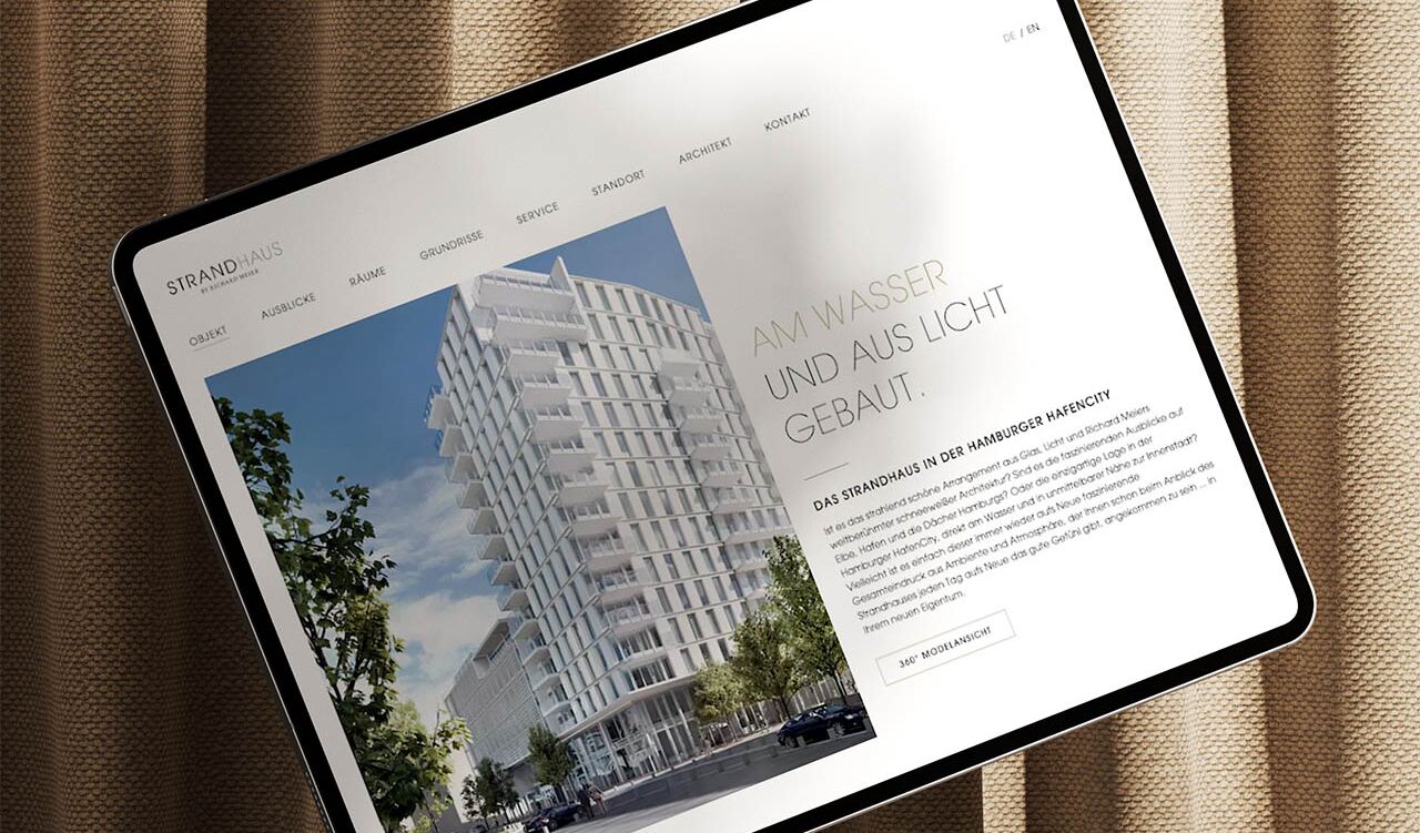 Tablet-Display – zeigt Rendering eines weißen, terrassenförmigen Wohnhochhauses – auf beige texturiertem Stoff liegend. Bildschirmtext: STRANDHAUS HAFENCITY; OBJEKT AUSBLICKE RÄUME GRUNDRISSE SERVICE STANDORT ARCHITEKT KONTAKT; DE / EN; AM WASSER UND AUS LICHT GEBAUT. DAS STRANDHAUS IN DER HAMBURGER HAFENCITY; 360° MODELANSICHT.