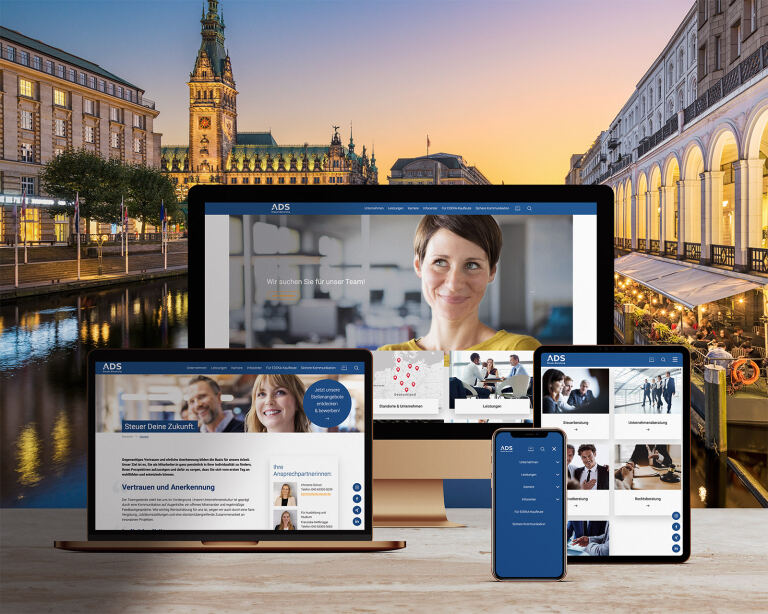 Mehrere Bildschirme (Desktop, Laptop, Tablet, Smartphone) zeigen geöffnete Unternehmenswebseiten; stehen auf Holztisch vor abendlichem Stadtkanal mit Rathaus und Arkaden. Text im Bild: ADS; Wir suchen Sie für unser Team!; Steuer Deine Zukunft.; Vertrauen und Anerkennung; Ihre Ansprechpartnerinnen.