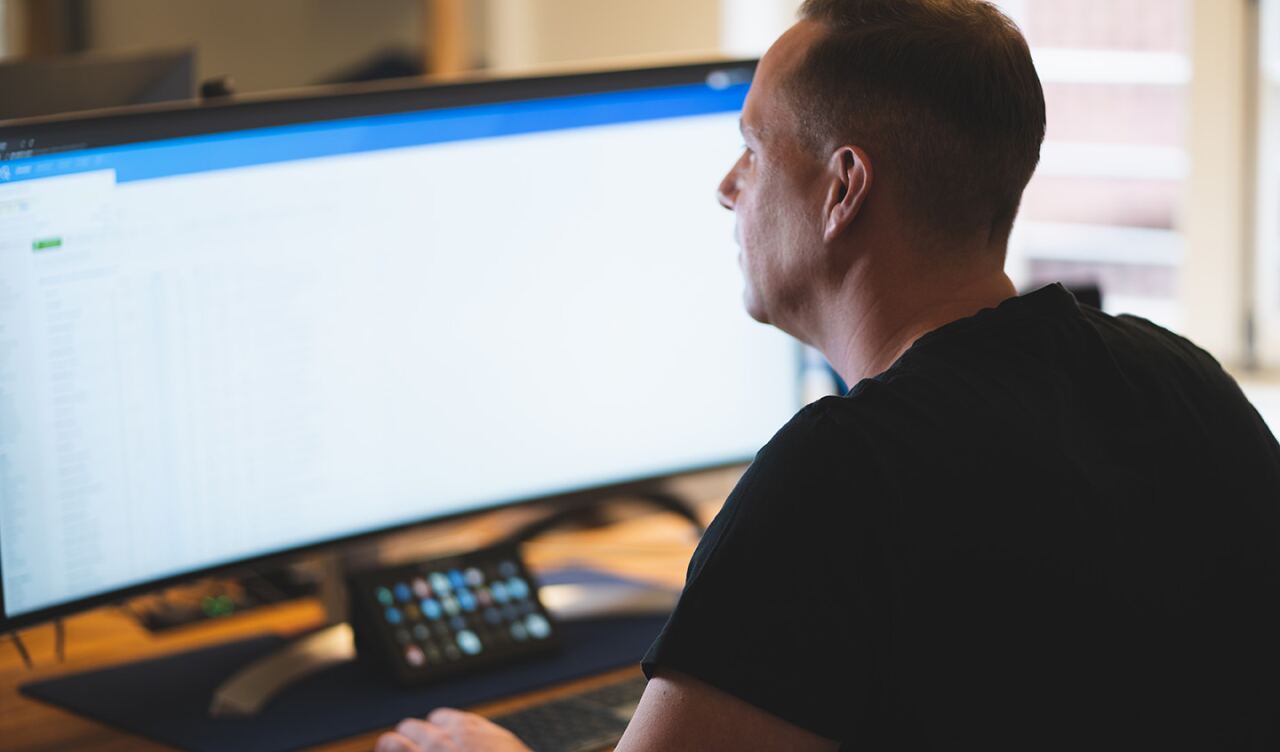 Entwickler von Homepage Helden programmiert ein individuelles Website-Template an einem Ultrawide-Monitor.
