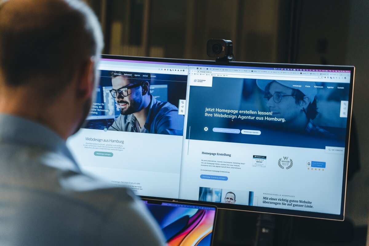 Blick über die Schulter auf einen Bildschirm mit der Website von Homepage Helden.